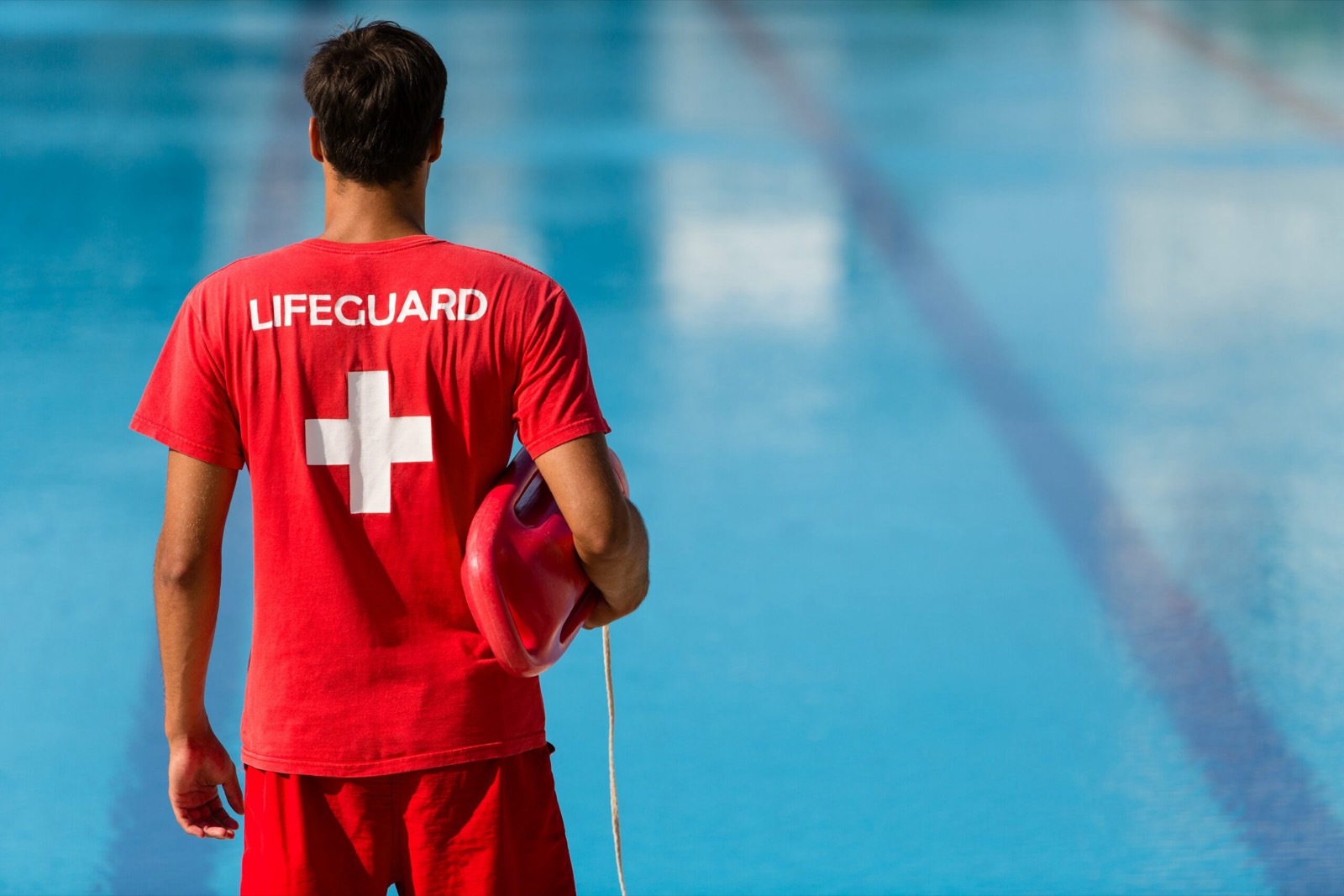 Assistente bagnanti con il rescue can a bordo di una piscina